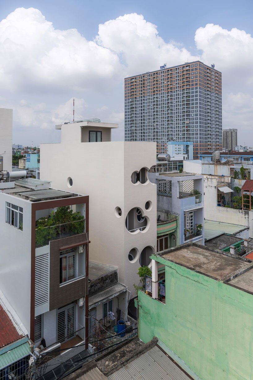cloud-shaped openings pierce urban co-living unit's concrete facade in vietnam