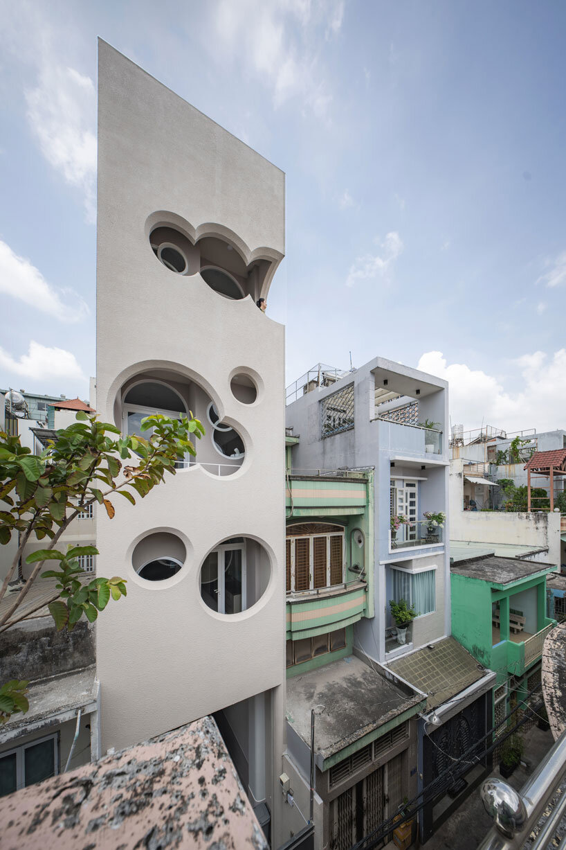 cloud-shaped openings pierce urban co-living unit's concrete facade in vietnam
