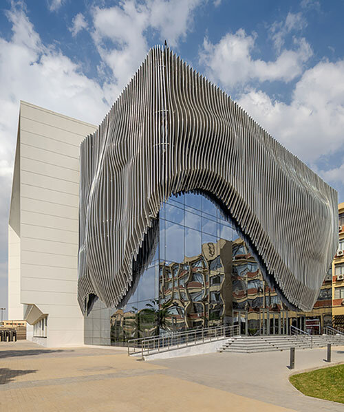 undulating aluminum curtain facade drapes over ain shams university theater in egypt