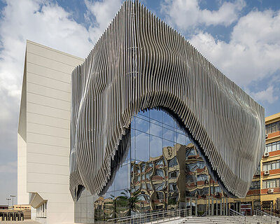 undulating aluminum curtain facade drapes over ain shams university theater in egypt