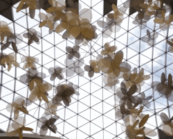 vincent leroy's kinetic installation of metallic mesh flowers floats above hainan island in china