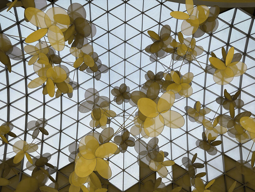 vincent leroy's kinetic installation of metallic mesh flowers floats above hainan island in china