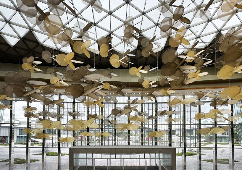 vincent leroy's kinetic installation of metallic mesh flowers floats above hainan island in china