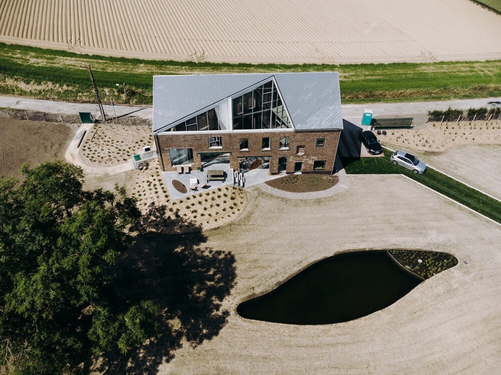 OYO architects carves triangular incision into farmhouse in rural belgium, bringing in light and air