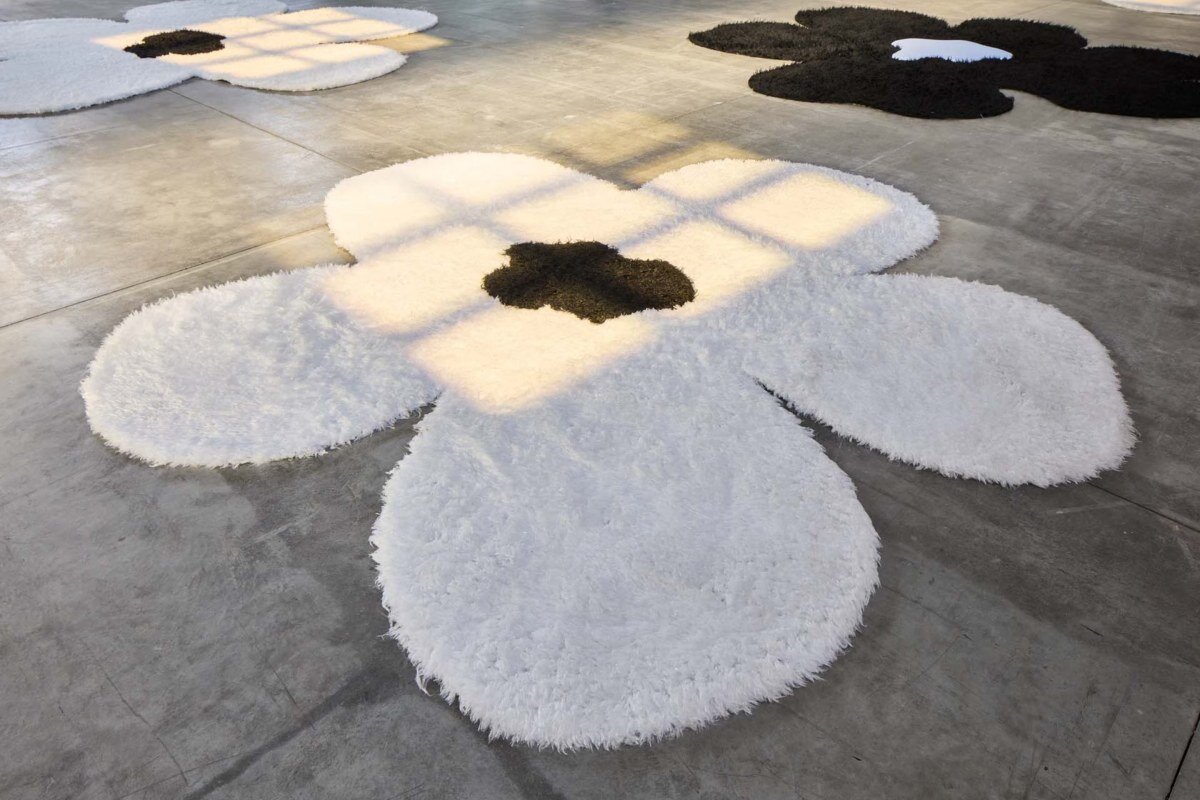 The islands of carpets with oma flowers flourish on the Prada's SS26 clothing showcase in Milan