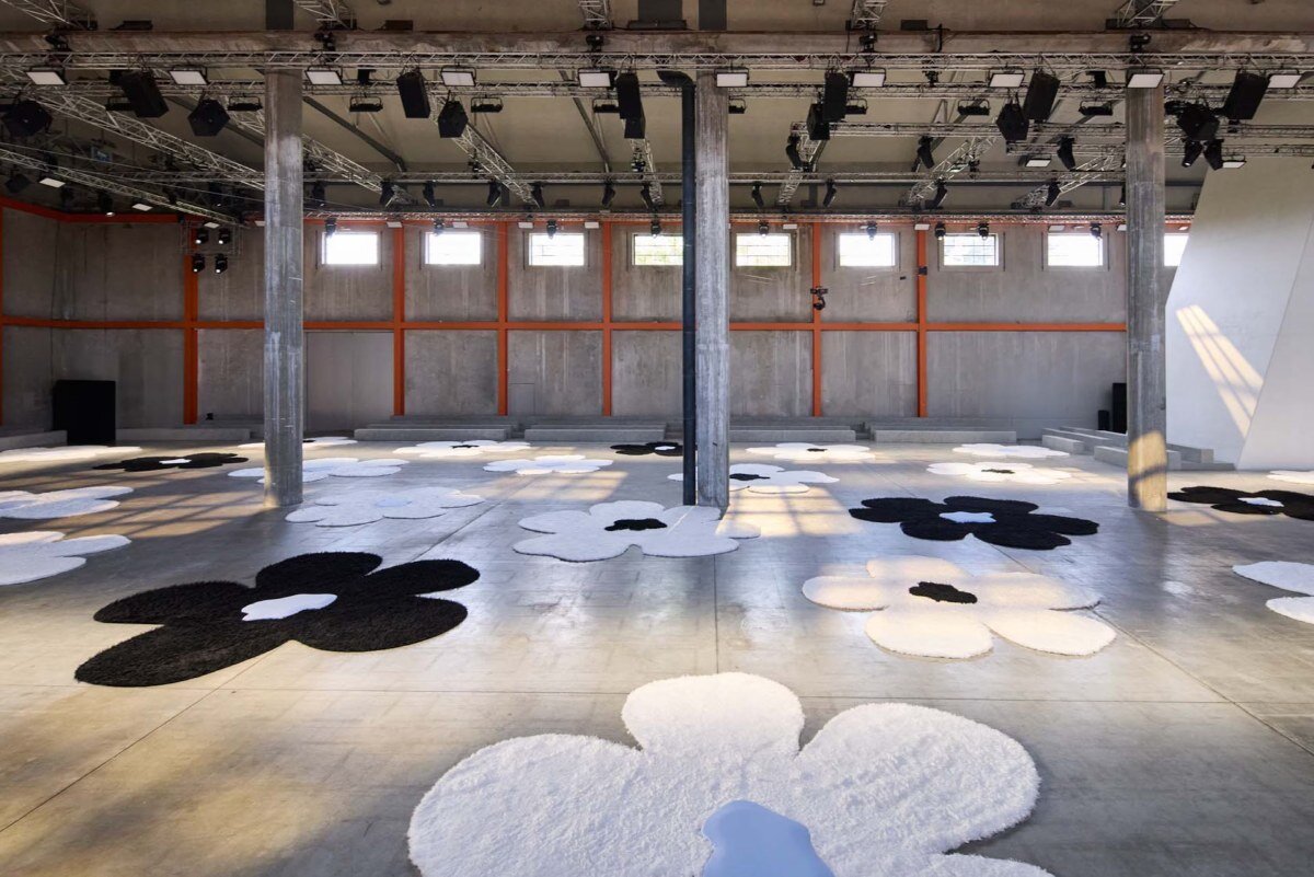 The islands of carpets with oma flowers flourish on the Prada's SS26 clothing showcase in Milan