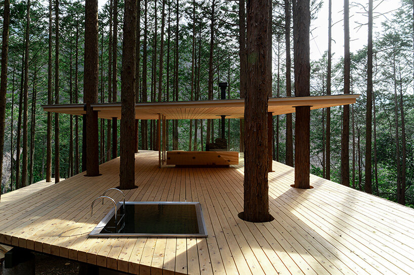 tree trunks pierce through sauna shelter by DAICHI in japanese forest