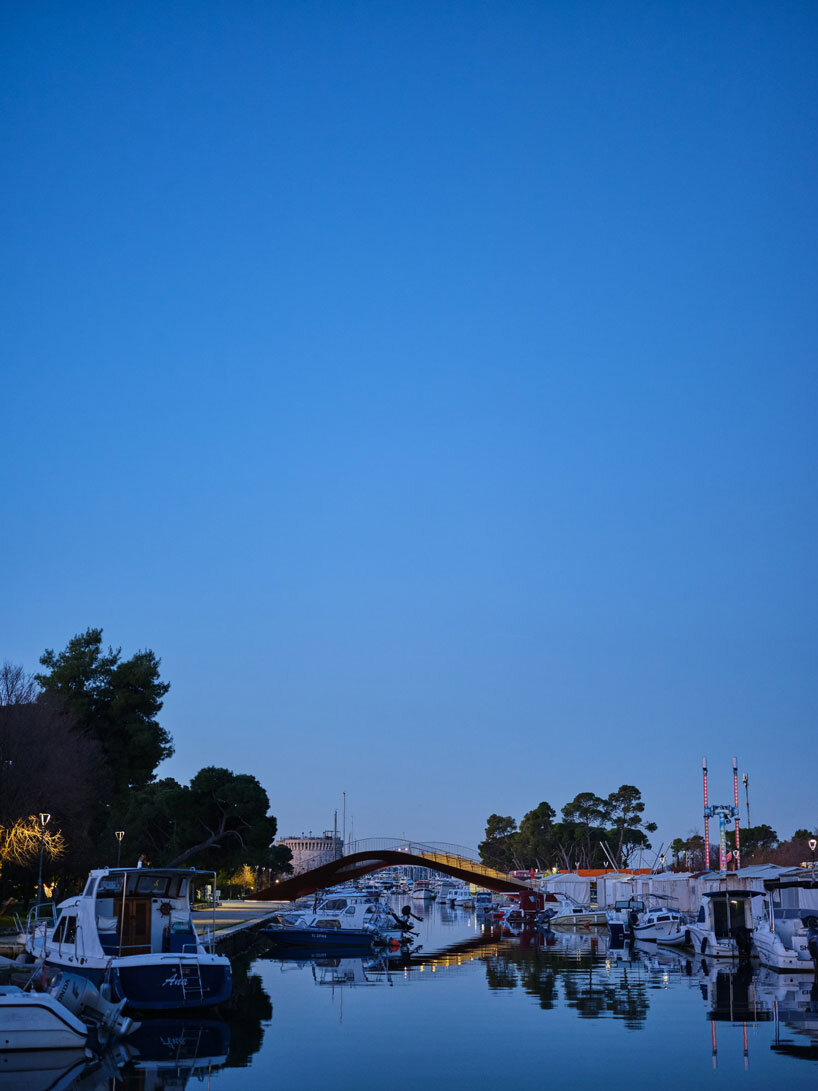 slender steel bridge with integrated net seating expands over foša port in croatia