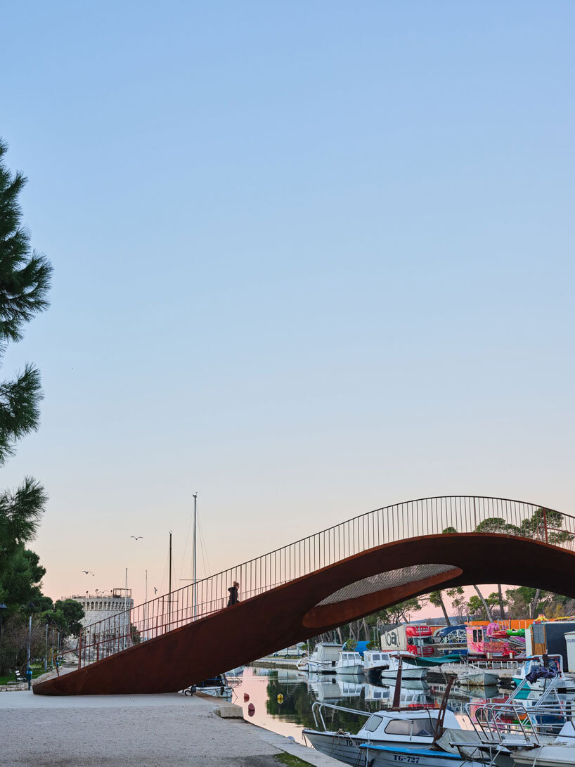 slender steel bridge with integrated net seating expands over foša port in croatia