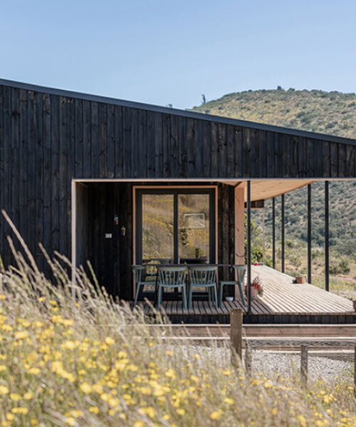 charred timber wraps linear casa las tupas, topped with pitched roof in northern chile