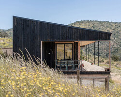 pitched roof tops linear casa las tupas, clad in charred timber in northern chile