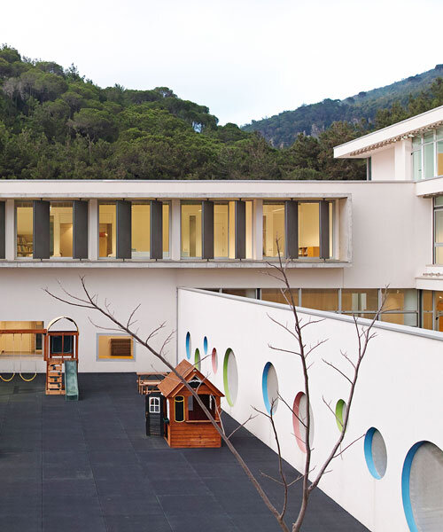 circular colored openings pierce through concrete facade of school extension in lebanon