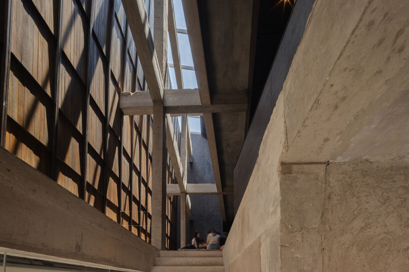 light and rain pour through internal courtyard within monochrome dessert shop in indonesia