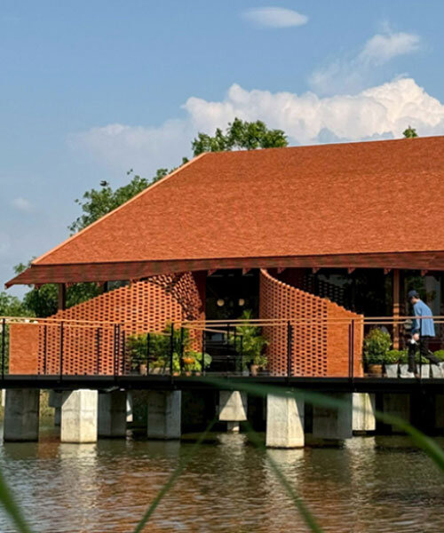 clad in terracotta tiles, morjor café floats above water pond in thailand