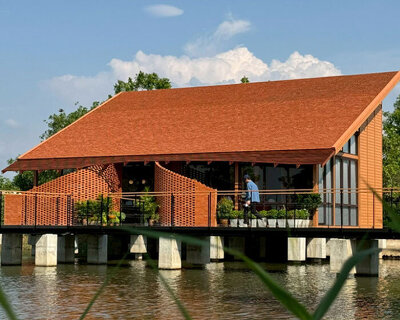 clad in terracotta tiles, morjor café floats above water pond in thailand