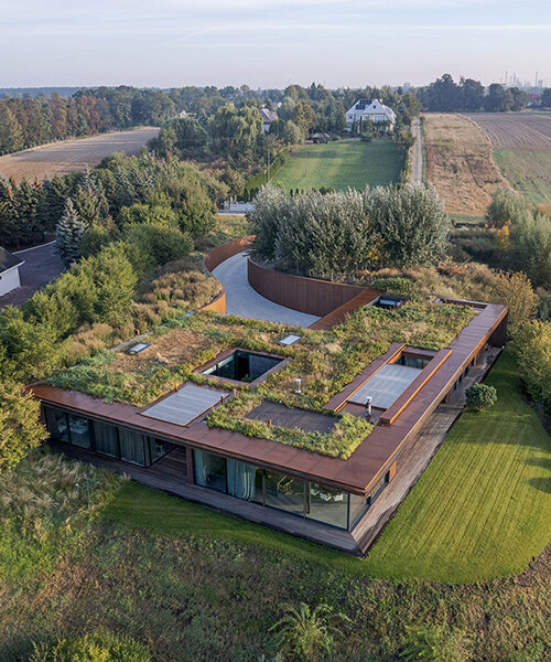 77 studio's 'house on the slope' camouflages beneath meadowed green roof in poland