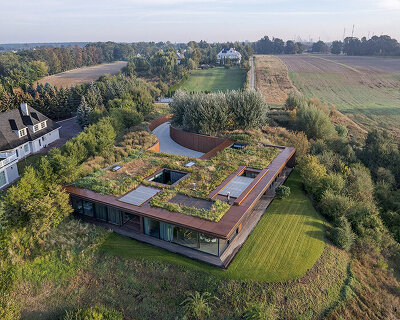 77 studio's 'house on the slope' camouflages beneath meadowed green roof in poland