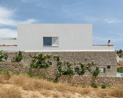 pieris.architects embeds layered stone-and-plaster residence into greek hillside