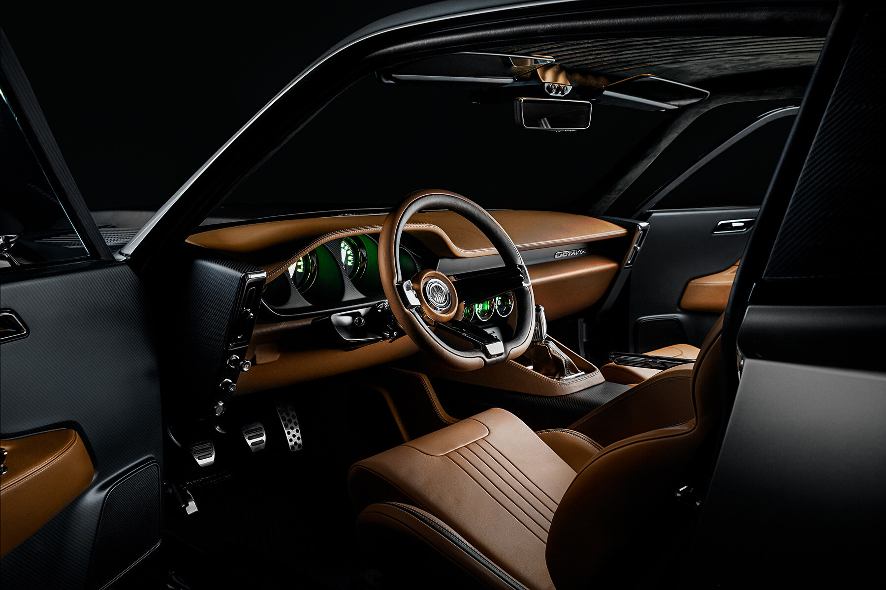 The image shows the interior of a sleek, modern car with a luxurious design. The seats and dashboard are upholstered in rich brown leather with fine stitching, complementing the black and carbon fiber accents throughout the cabin. The steering wheel has a sporty, retro-inspired design with metallic details, and the instrument cluster behind it features green-lit gauges that add a futuristic touch. The overall atmosphere is one of high-end craftsmanship and advanced technology, with well-integrated controls and a minimalist, driver-focused layout.