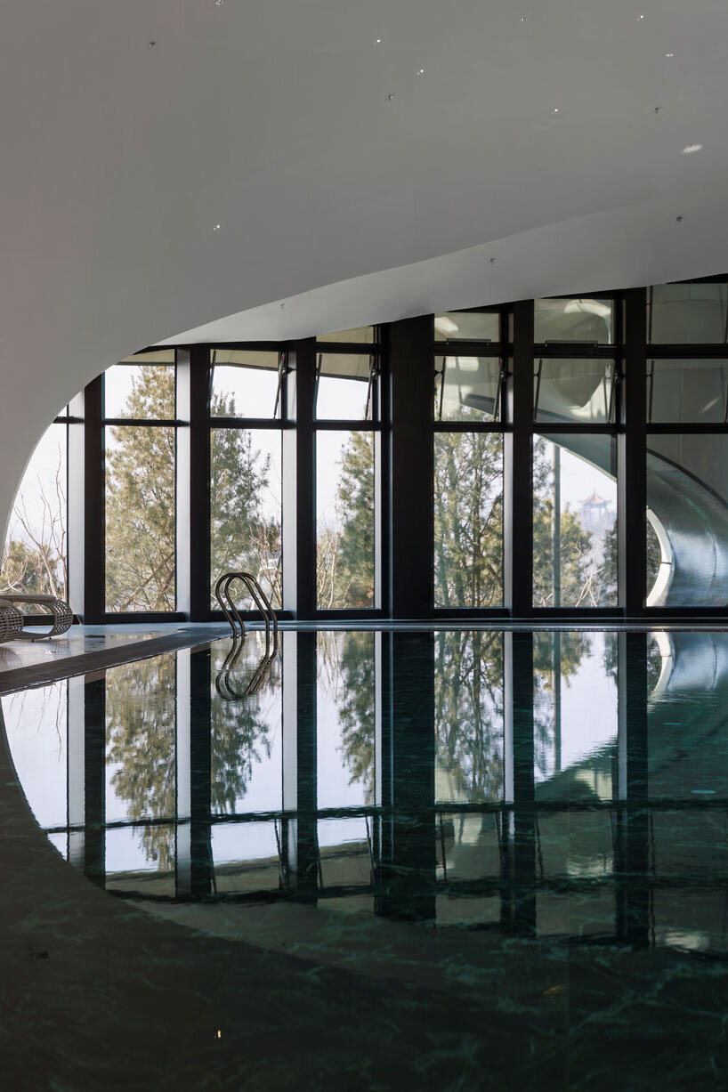 wutopia lab carves soft white caving interiors for pebble-shaped mountain hotel in china