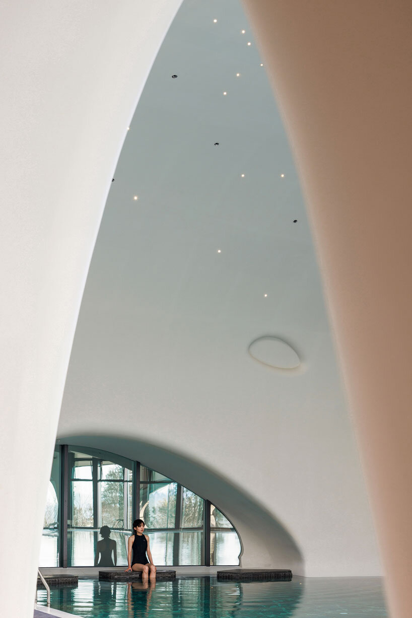 wutopia lab carves soft white caving interiors for pebble-shaped mountain hotel in china