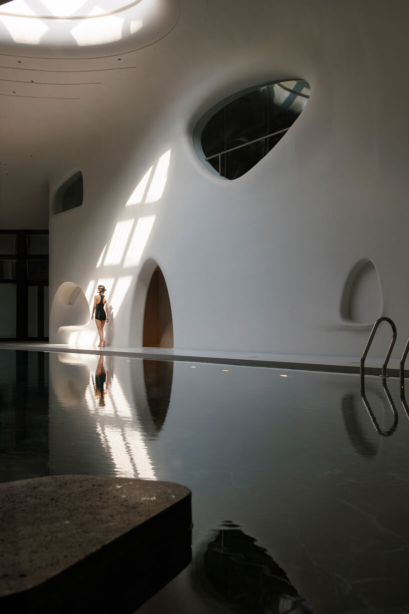 wutopia lab carves soft white caving interiors for pebble-shaped mountain hotel in china