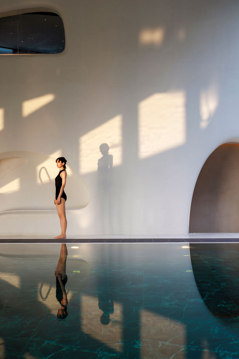 wutopia lab carves soft white caving interiors for pebble-shaped mountain hotel in china