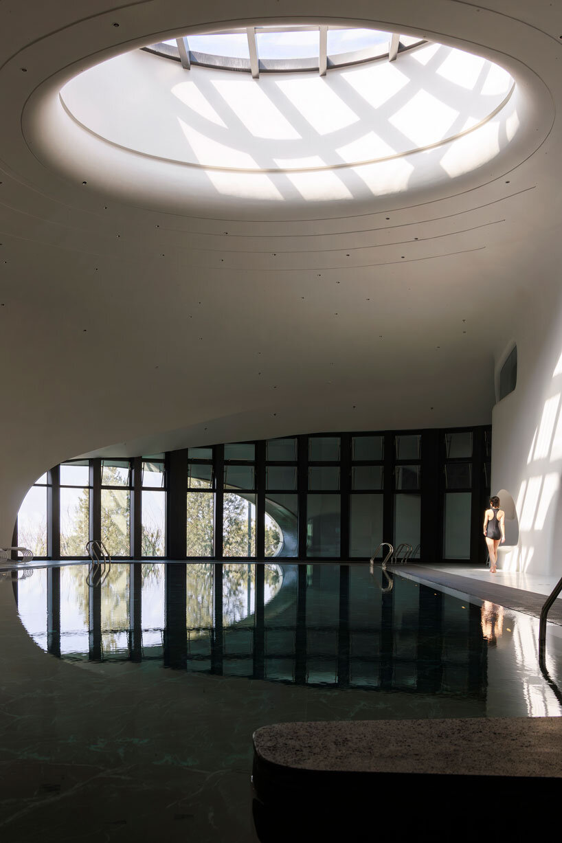 wutopia lab carves soft white caving interiors for pebble-shaped mountain hotel in china