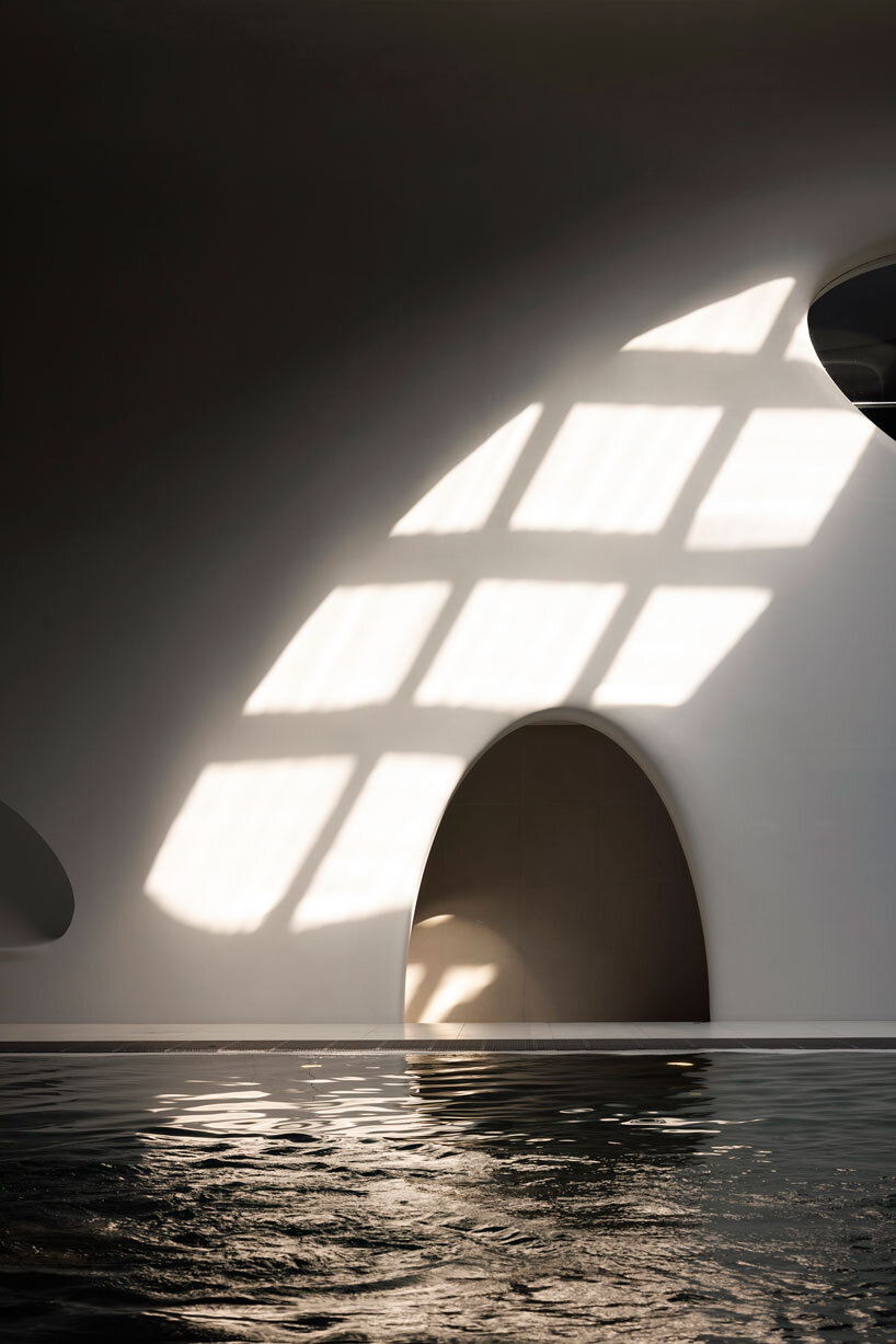 wutopia lab carves soft white caving interiors for pebble-shaped mountain hotel in china