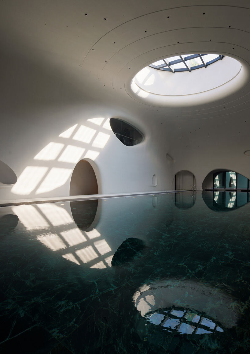 wutopia lab carves soft white caving interiors for pebble-shaped mountain hotel in china