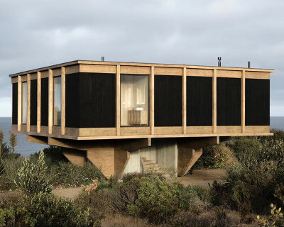 wooden beams sit atop concrete spiral staircase in lote studio’s elevated casa CG in chile