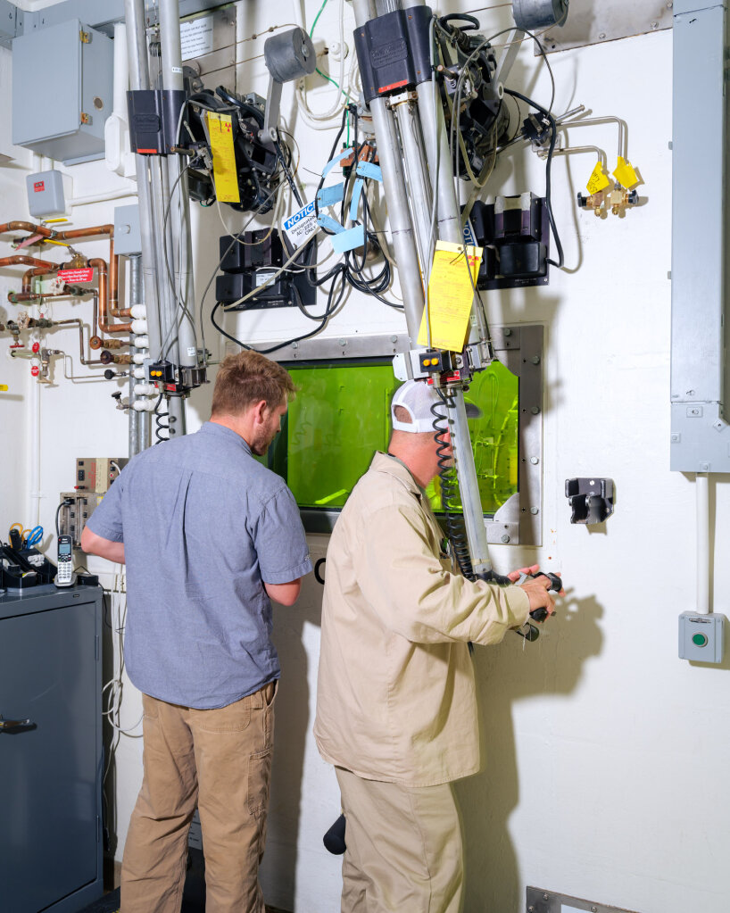 technicians use remote manipulators to handle actinium-225 inside a hot cell