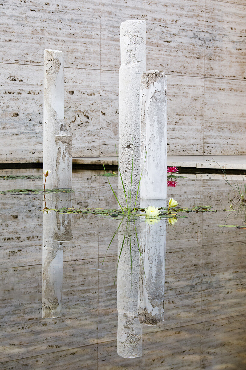 concrete sculptures surface from the pond of mies van der rohe's barcelona pavilion