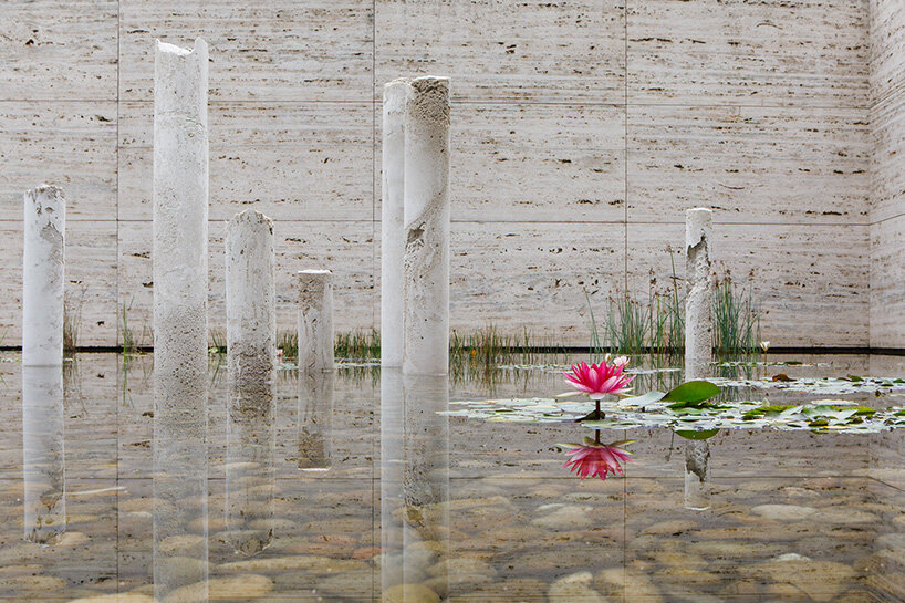 concrete sculptures surface from the pond of mies van der rohe's barcelona pavilion