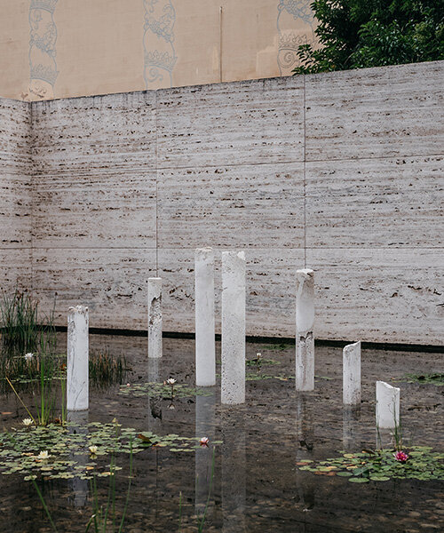 concrete sculptures surface from the pond of mies van der rohe's barcelona pavilion