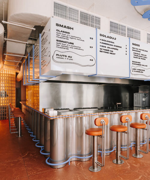 caramel tones and fluid undulating lines form melting interior of pluto burger bar in poland