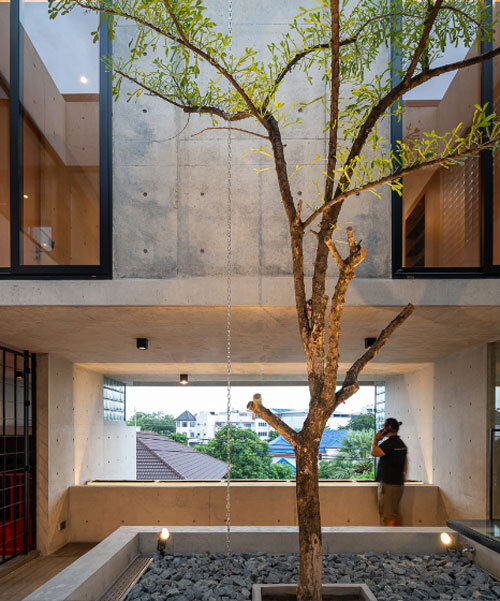 green courtyard anchors hybrid home and office within concrete structure in bangkok