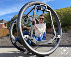 bike with large moving rings and bucket seat rolls the user around without pedaling