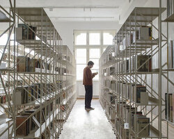 suspended steel shelving forms permeable curtain within revitalized historic slovak library