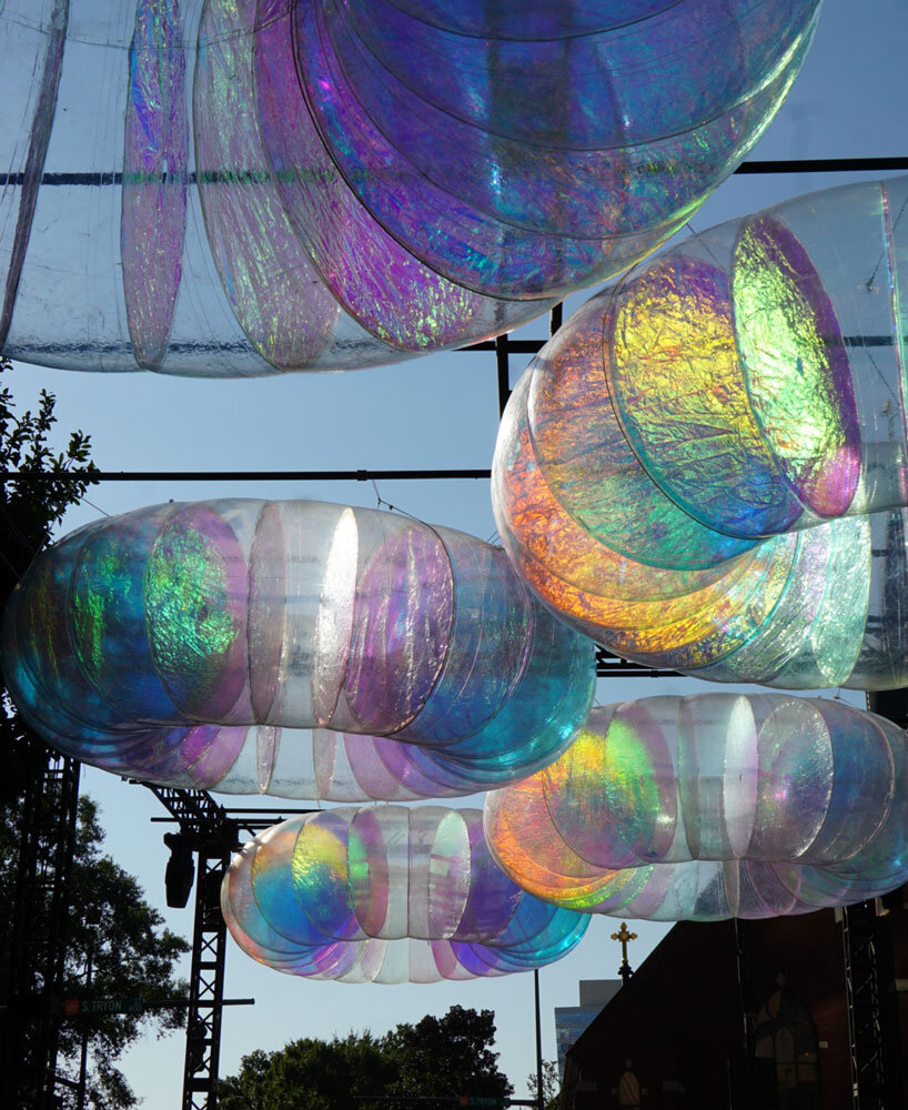floating oculus installation shimmers in shifting chromatic light above brooklyn's streets