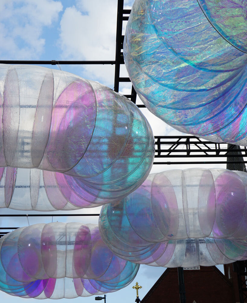 floating oculus installation shimmers in shifting chromatic light above brooklyn's streets