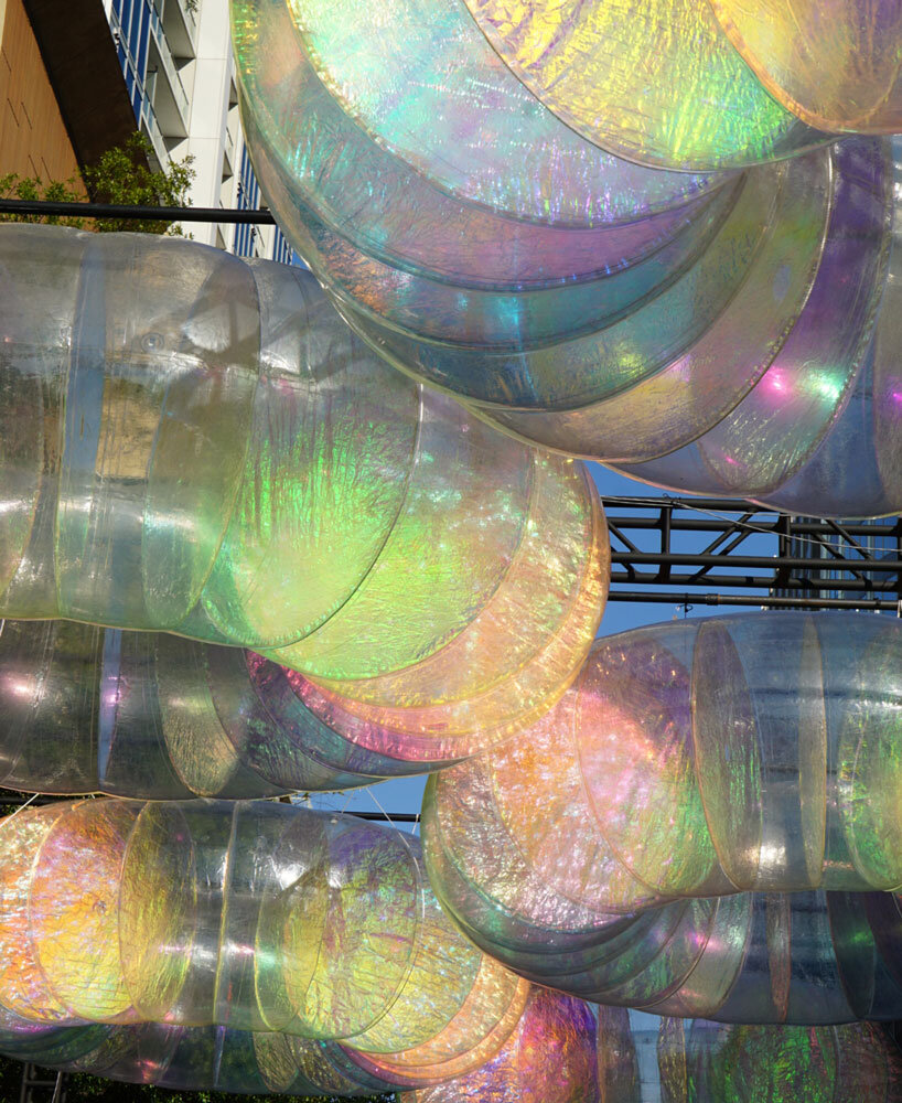 floating oculus installation shimmers in shifting chromatic light above brooklyn's streets