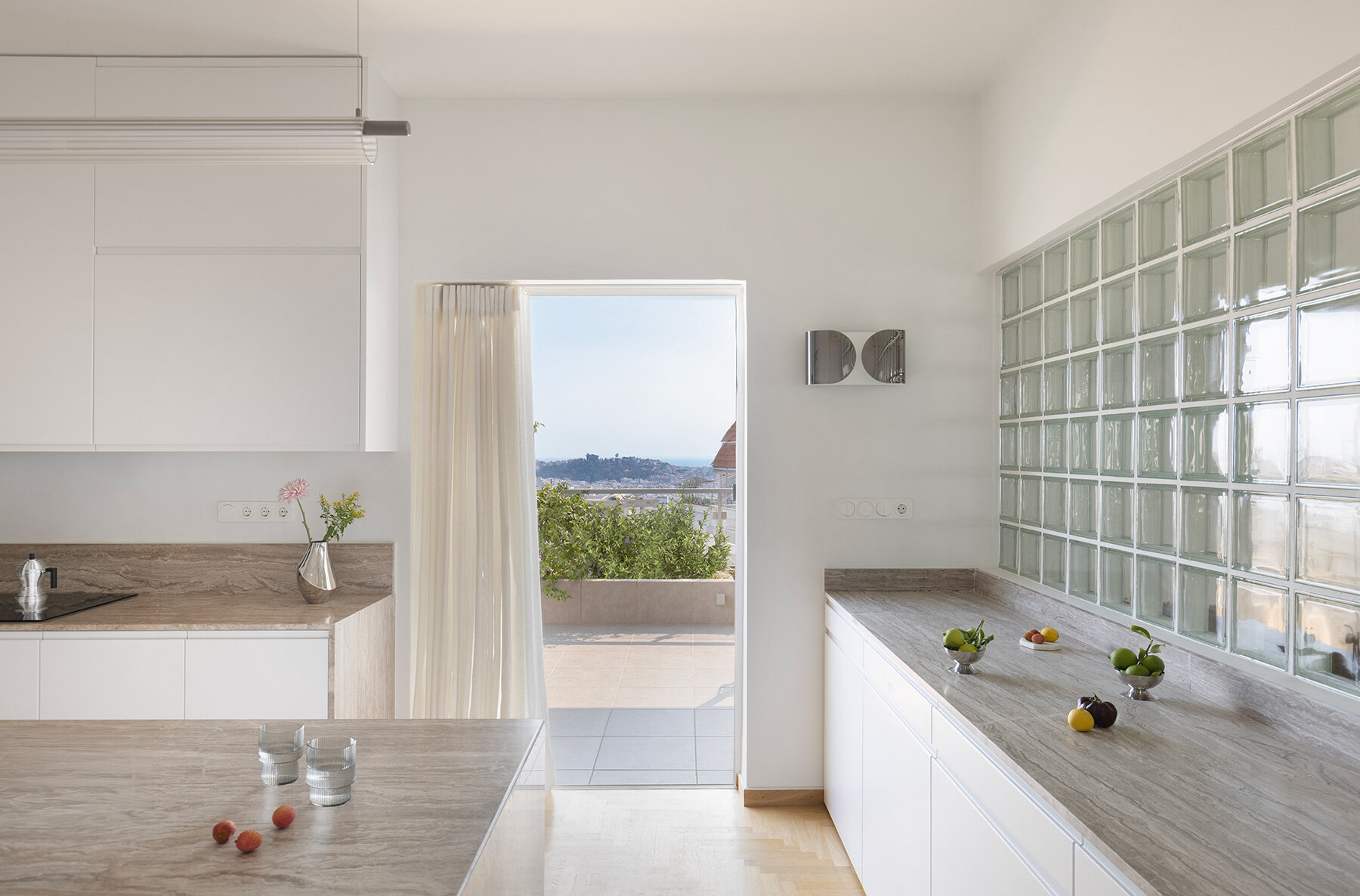 Bloques de vidrio y superficies de mármol iluminan la renovación del ático de Atenas de los años 60