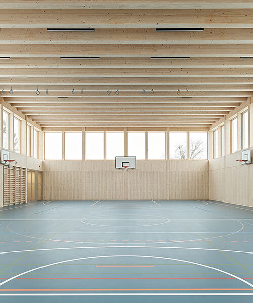 vertical timber construction shapes twin stacked sports halls in switzerland by kit