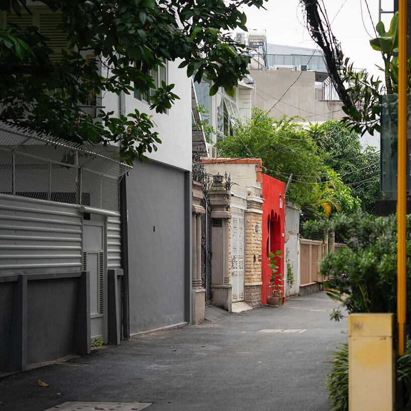 La fachada roja de un café vietnamita tiene una entrada tallada con la forma de una mano acogedora.