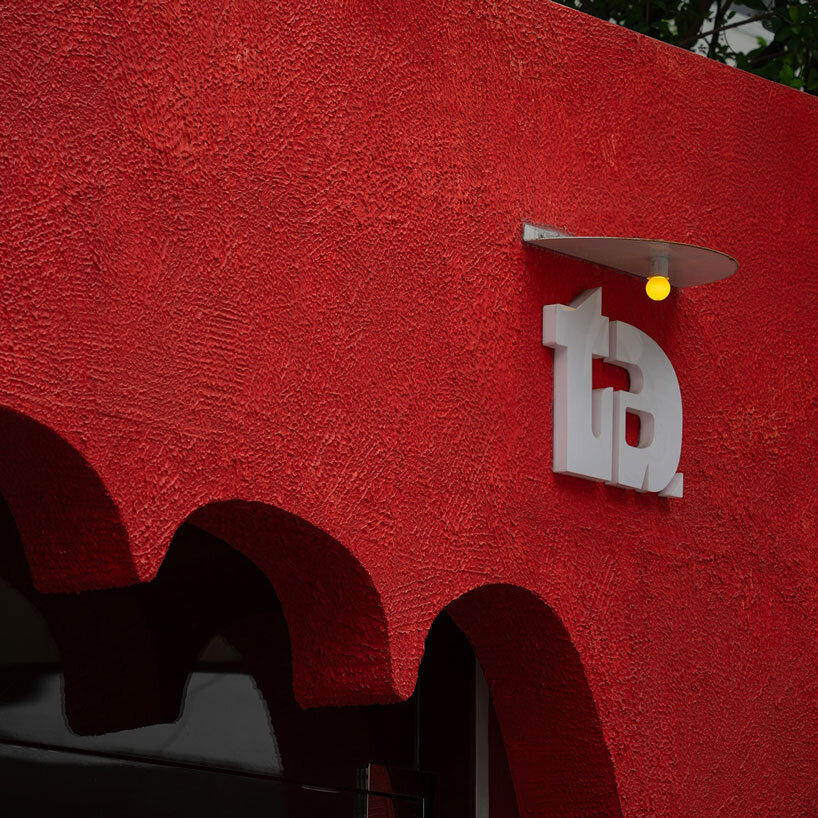La fachada roja de un café vietnamita tiene una entrada tallada con la forma de una mano acogedora.