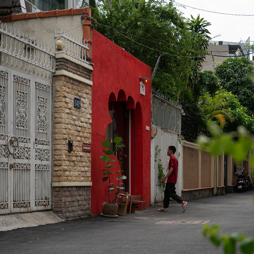La fachada roja de un café vietnamita tiene una entrada tallada con la forma de una mano acogedora.