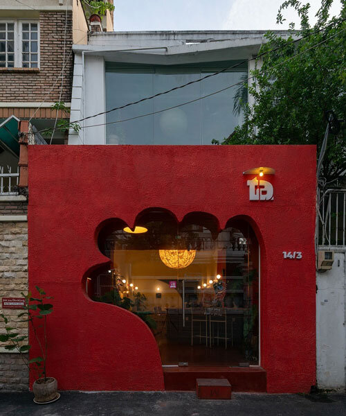 café’s red facade carves welcoming hand-shaped entrance in vietnam