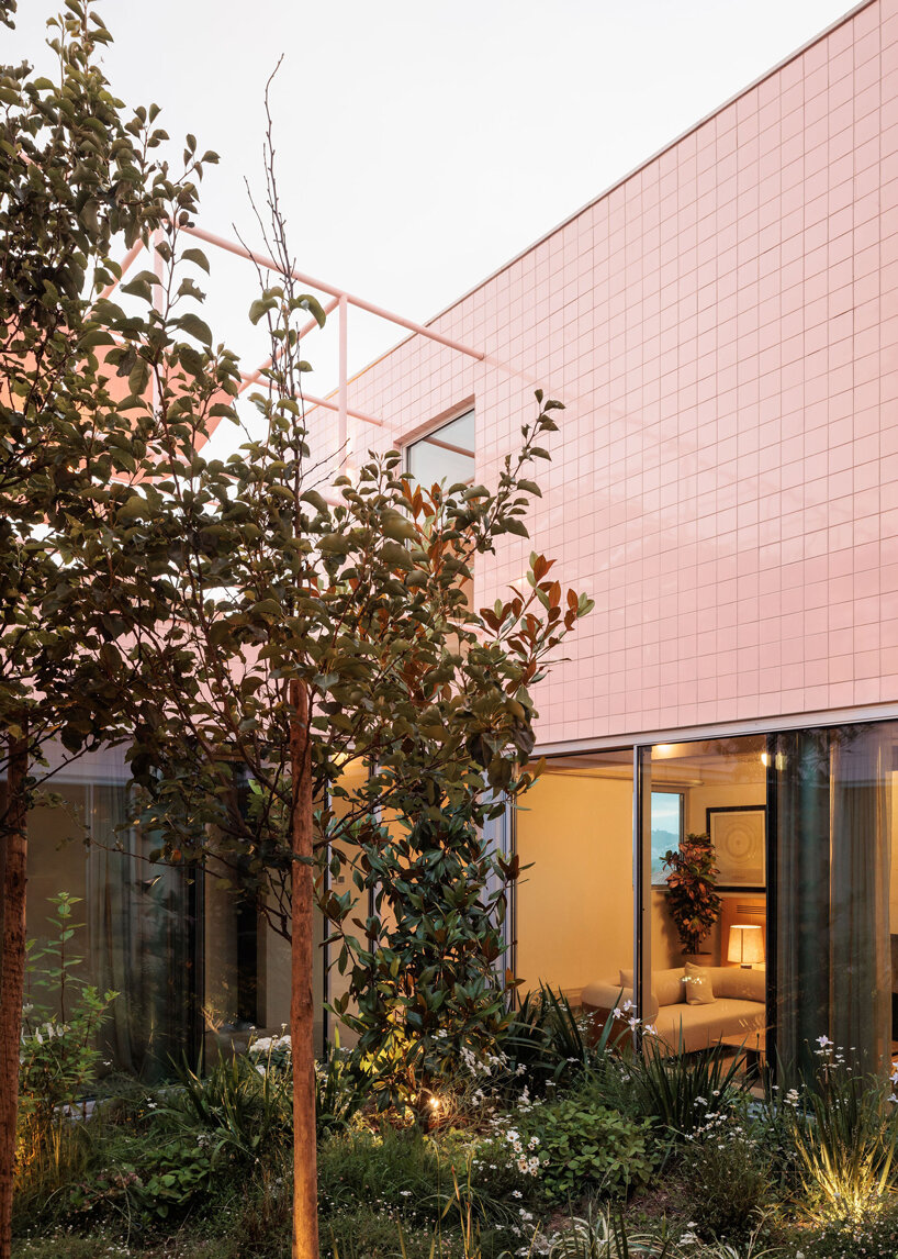 atelier RUA's light pink house contrasts with surrounding greenery in portugal