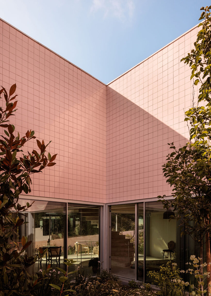 atelier RUA's light pink house contrasts with surrounding greenery in portugal
